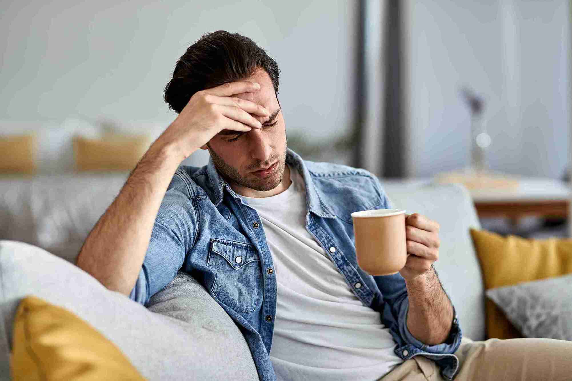 youg stresed man drinking coffee on a sofa