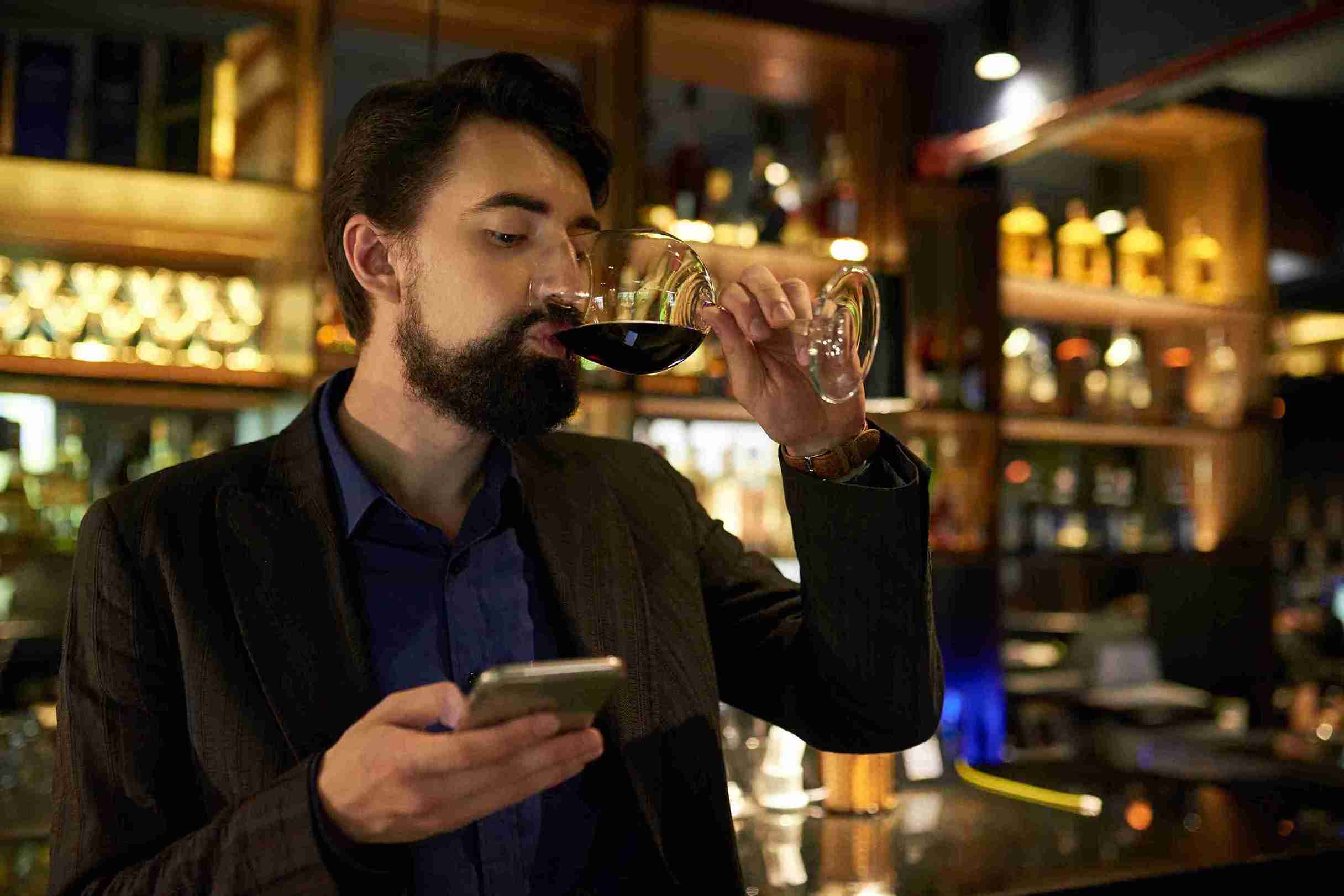 young man drinking and texting on mobile